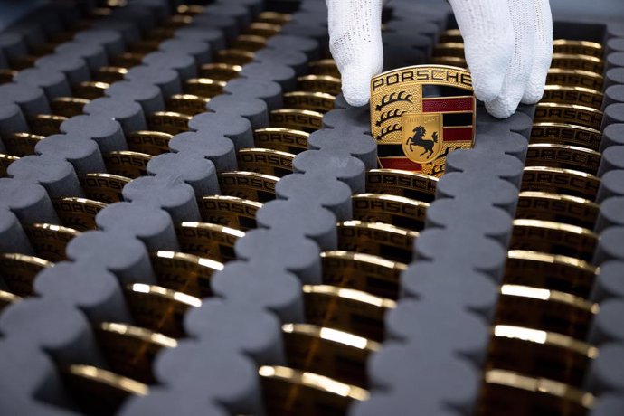 26 September 2022, Baden-Wuerttemberg, Stuttgart: A Porsche AG employee shows the Porsche logo in a production hall at Porsche's main plant. The Volkswagen Group is to take its sports car subsidiary Porsche AG public. Photo: Marijan Murat/dpa