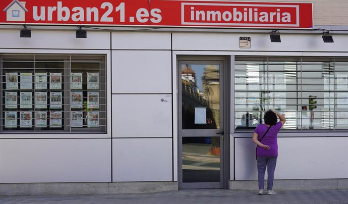 Archivo - Una señora mirando un escaparate de una inmobiliaria.