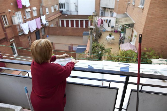 Archivo - Una mujer tiende ropa en su balcón