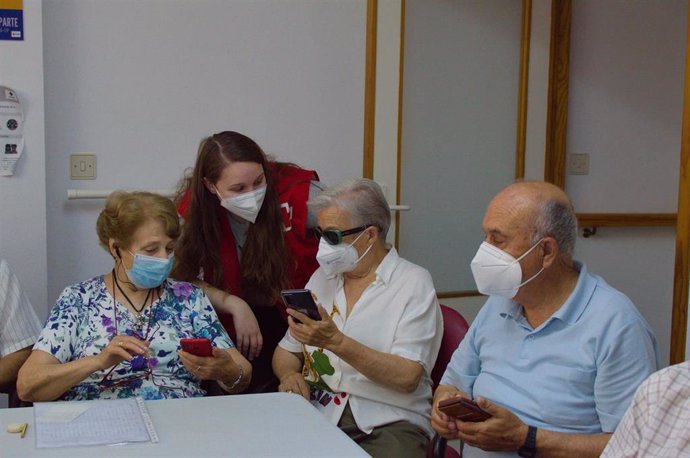Una voluntaria de Cruz Roja con un grupo de personas mayores.
