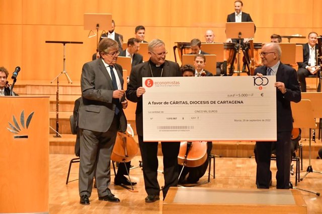 El Obispo, José Manuel Lorca Planes, y el director de Cáritas, José Antonio Planes, reciben el cheque de 5.000 euros en el escenario antes del comienzo del Concierto