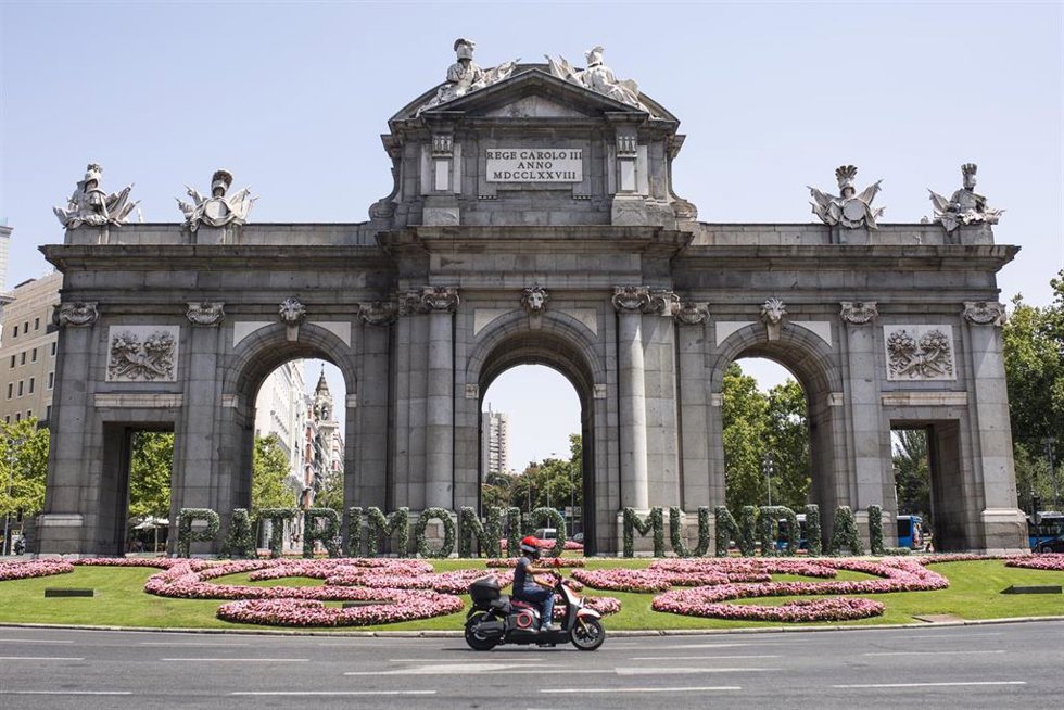 Archivo - Una moto pasa por las letras gigantes que forman la palabra Patrimonio Mundial en la Puerta de Alcalá.