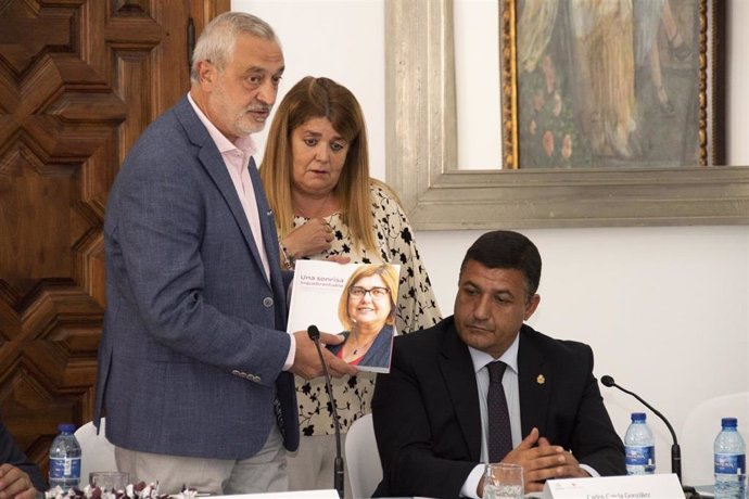 El presidente de la Diputación de Cáceres entrega a Toñi Cordero, hermana de Charo Cordero, un libro con los actos más importantes a los que su hermana asistió en los cinco años al frente de la diputación cacereña