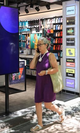 Archivo - Una mujer pasa por una tienda Phone House, a 26 de julio de 2022, en Madrid (España).