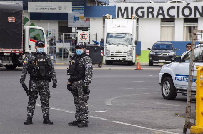 Archivo -  Dos agentes antinarcóticos de la policía nacional ecuatoriana con protectores bucales esperan a los vehículos en la frontera con Colombia para realizar controles de rutina, en medio del brote de Coronavirus.