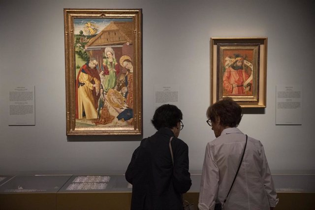 Dos mujeres frente a dos de las obras de la exposición 'Marqués de Santillana. Imágenes y letras' en el Museo del Prado.
