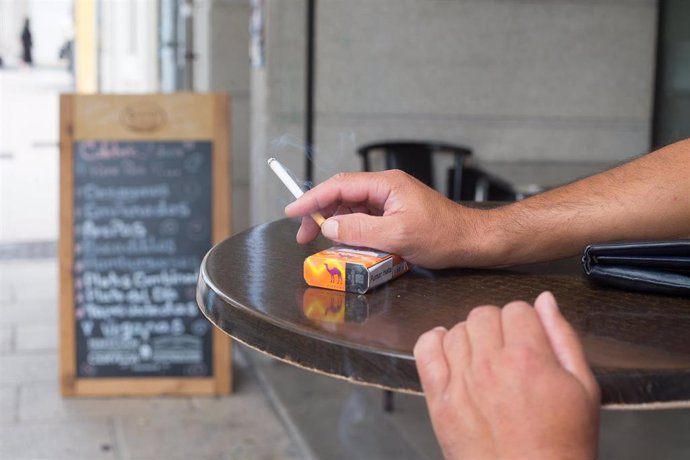 Archivo - Una persona fuma en una terraza durante el primer día de la prohibición de realizarlo en la vía pública en Galicia si no existe una distancia de dos metros de separación con otras personas para evitar contagios de Covid-19, en Lugo, Galicia, (