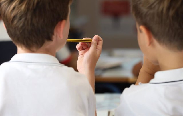Un niño sostiene un lápiz en el colegio.
