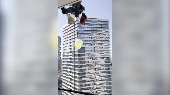 Esta chica da de comer a unos limpiadores de ventanas...¡Mientras cuelgan a cientos de metros del suelo!