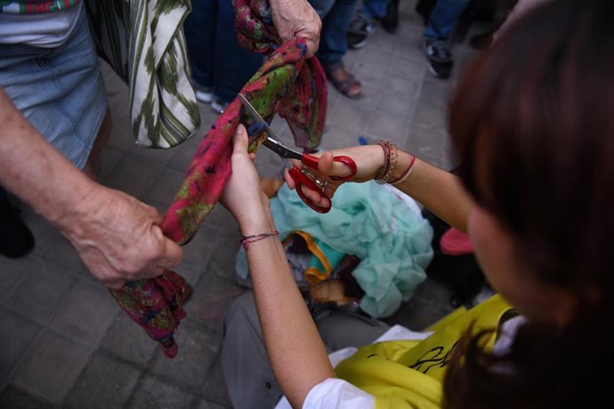 Una mujer corta una tela en una concentración contra la muerte de dos mujeres iraníes, frente a la embajada de Irán, a 6 de octubre de 2022, en Madrid (España)