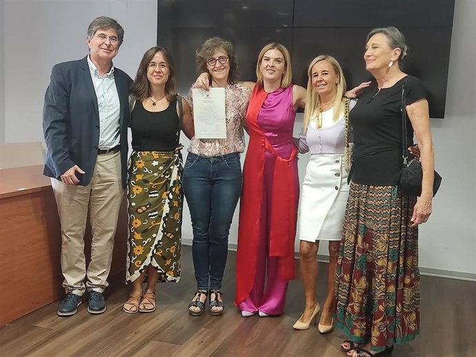 Nieves Muñoz (centro) muestra el título acreditativo de su doctorado.