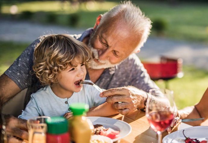 Archivo - Abuelo y nieto comiendo.