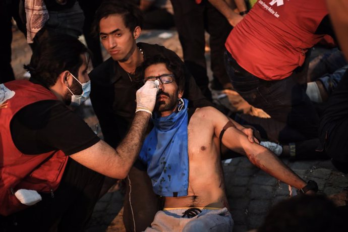 FILED - 01 October 2022, Iraq, Baghdad: Iraqi medics attend to an injured protester during clashes at a demonstration marking the third anniversary of the 2019 anti-government protests. Photo: Ameer Al-Mohammedawi/dpa
