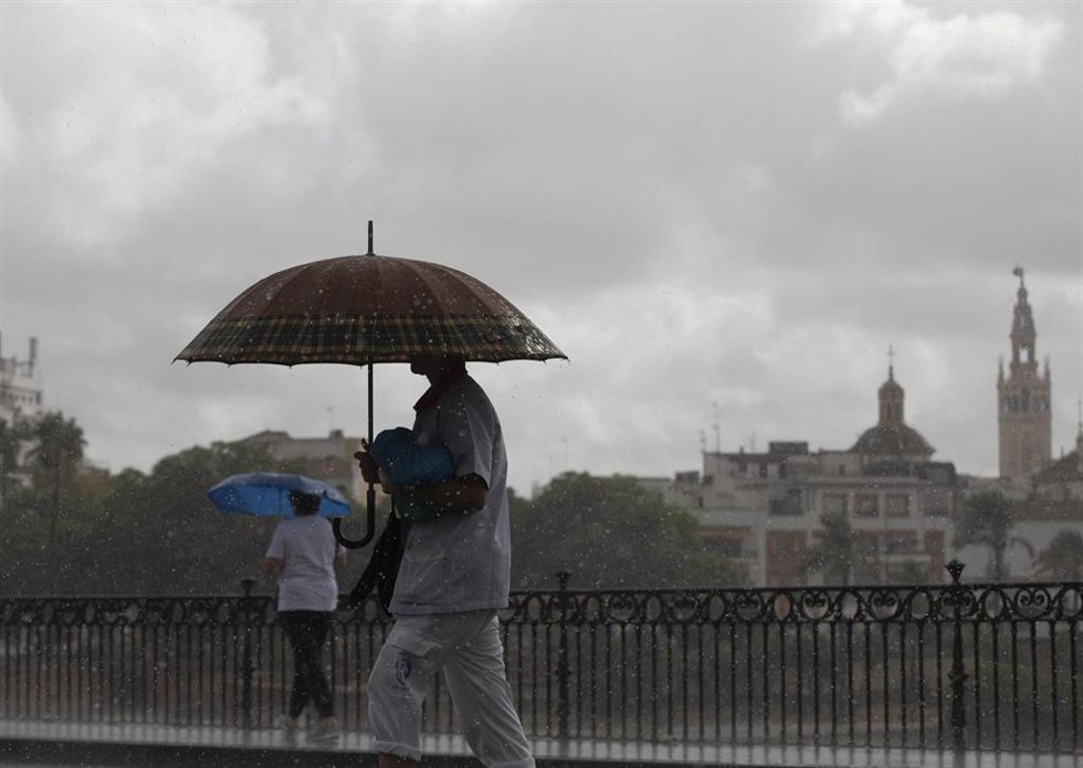 Dos personas caminan bajo sus paraguas en Sevilla.