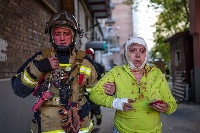 Un miembro de los servicios de emergencia ucranianos acompaña a una mujer herida por los bombardeos en Kiev