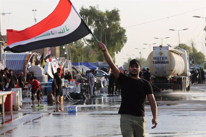 Archivo - Un seguidor del clérigo Muqtada al Sadr ondea la bandera de Irak en una protesta del 8 de agosto