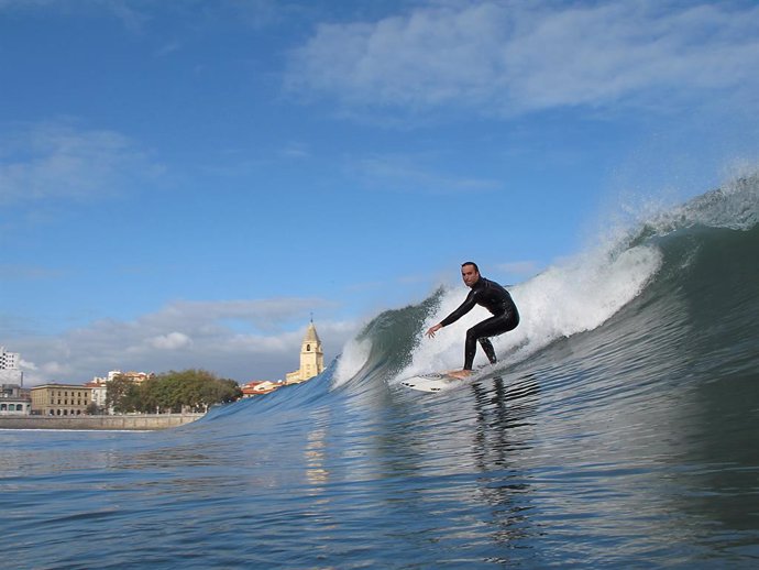 Archivo - Un hombre haciendo surf en la playa de San Lorenzo de Gijón. 