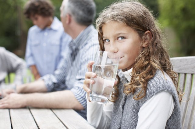 Niña bebiendo un vaso de agua.