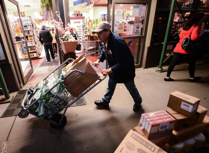 Archivo - 13 March 2020, US, New York: A worker transports goods to a supermarket because a panic-buying fever due to the coronavirus outbreak. Photo: William Volcov/ZUMA Wire/dpa