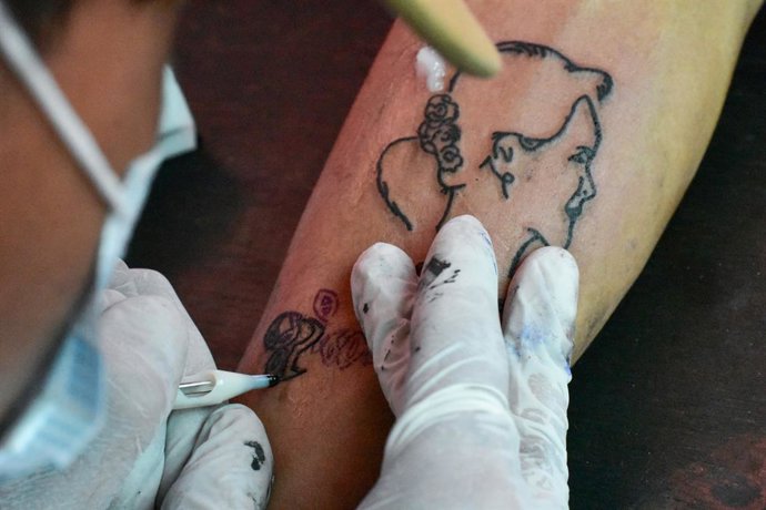 Archivo - 02 March 2021, Myanmar, Nyaung Shwe: A tattoo artist inks a portrait of Myanmar's ousted head of government, Aung San Suu Kyi, on one of her supporters. Supporters of Aung San Suu Kyi are getting her face tattooed on their skin to show solidar