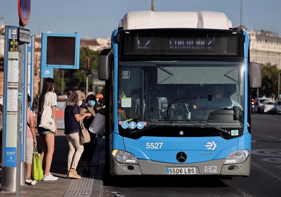 Archivo - Varias personas, con mascarilla, hacen cola para subir a un autobús de la Empresa Municipal de Transportes madrileña (EMT), en Madrid (España). 