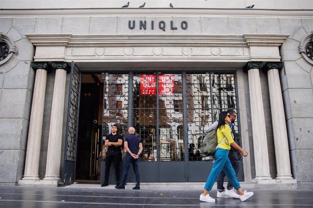 Dos personas pasan por delante de la entrada de una tienda Uniqlo en la Gran Vía, la segunda que abre en Madrid, a 5 de octubre de 2022, en Madrid (España). El nuevo local de la cadena de tiendas de ropa japonesa cuenta con más de 2.000 metros cuadrados d