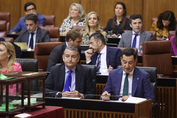El consejero de la Presidencia, Interior, Diálogo Social y Simplificación Administrativa, Antonio Sanz (i), y el presidente de la Junta, Juanma Moreno (d), en el Pleno del Parlamento andaluz.