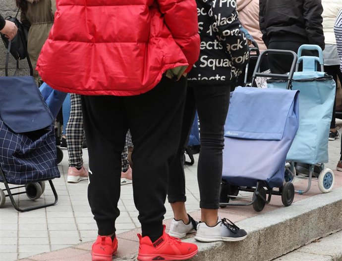 Archivo - Varias personas hacen cola para recoger una cesta navideña.