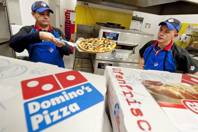 Archivo - FILED - 04 November 2010, Berlin: A staff member of US pizza chain Domino Pizza hands a pizza to a customer in the chain's first German chain store in Berlin. Photo: Robert Schlesinger/dpa-Zentralbild/dpa