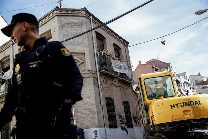 Un agente de Policía Nacional frente a una máquina retroexcavadora durante la demolición del edificio okupado La Higuera.