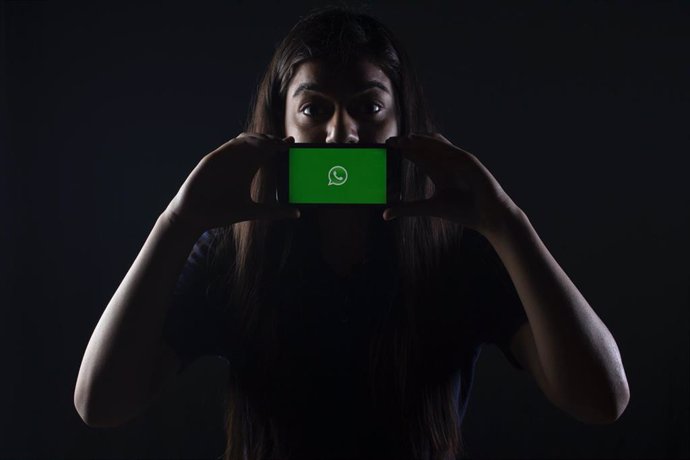 Una chica con un móvil con el icono de WhatsApp