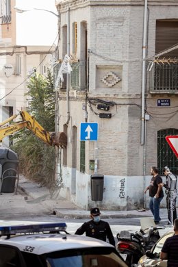 Varios agentes de Policía Nacional mientras una máquina retroexcavadora trabaja durante la demolición del edificio okupado La Higuera, en el barrio de Tetuán.