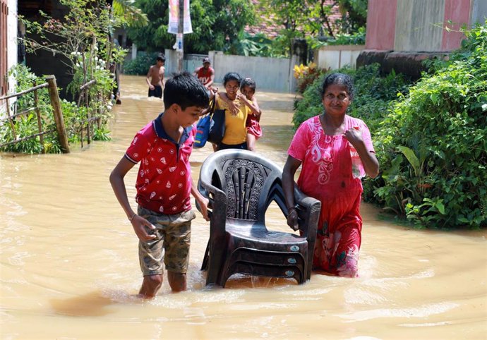 Varias personas trasportan objetos en calles inundadas por las fuertes lluvias en Sri Lanka. Archivo.