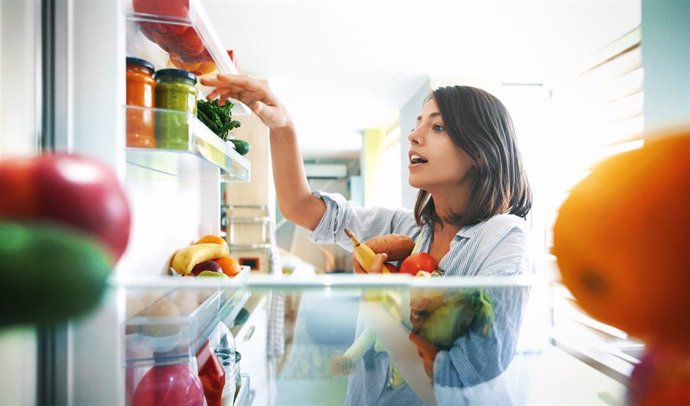 Archivo - Mujer cogiendo alimentos del frigorífico.