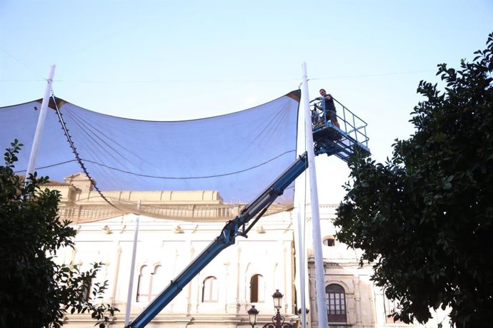 Operario trabajando en el desmontaje de los toldos en la Plaza de San Francisco de Sevilla.