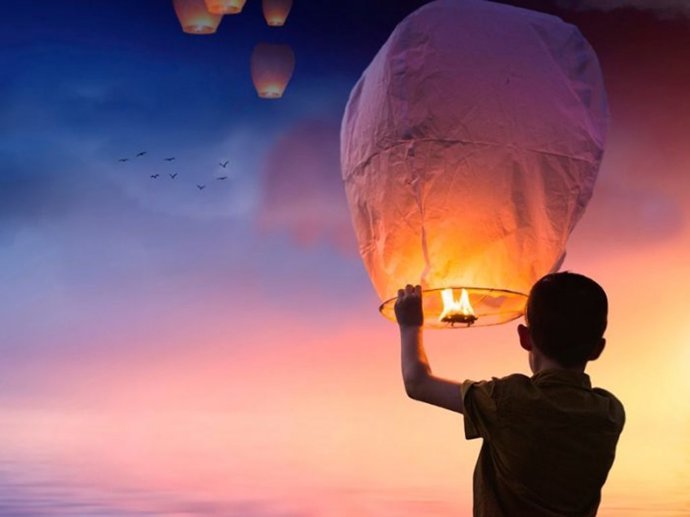 Un niño sujeta un farolillo volador.