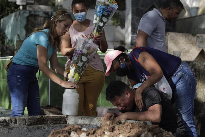  Los familiares de dos víctimas de las inundaciones y el corrimiento de tierras entierran los restos en el cementerio municipal de la ciudad. 