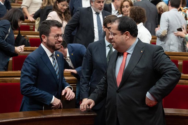 El presidente de la Generalitat, Pere Aragonès (i), le guiña el ojo al conseller de Interior Joan Ignasi Elena, durante la presentación del nuevo Govern de Esquerra Republicana de Catalunya durante una sesión de control en el Pleno del Parlament, a 19 de 