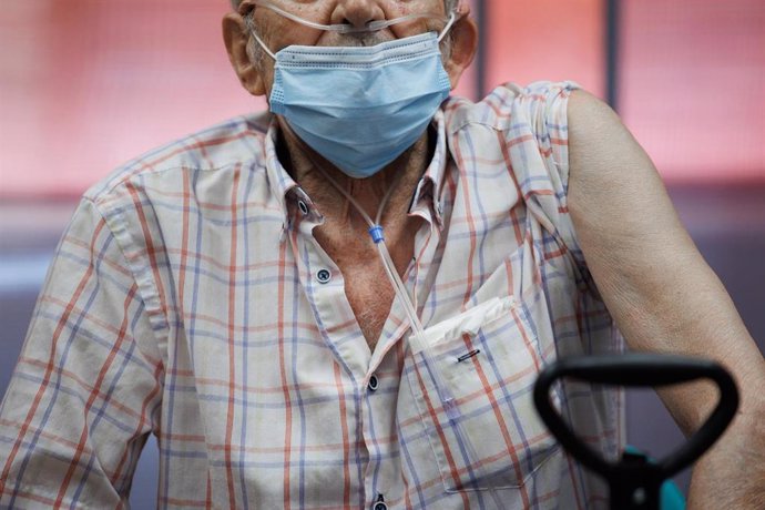 Un anciano prepara su brazo para la inyección de la dosis Moderna durante el inicio de la administración de la cuarta dosis de la vacuna frente al COVID-19