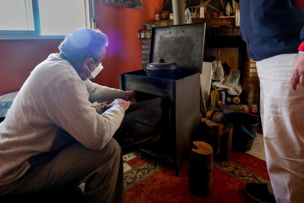 Archivo - Un hombre calienta una estufa en su vivienda del Sector 6 de la Cañada Real.