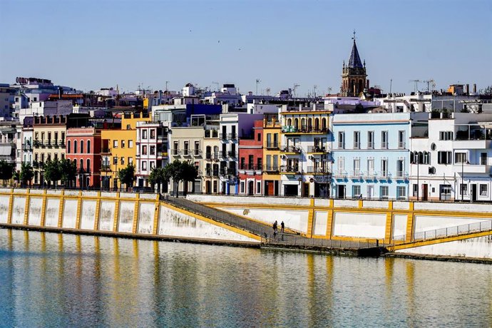 Archivo - La calle Betis del barrio de Triana vista desde la otra orilla, con la torre de la Iglesia de Santa Ana al fondo.