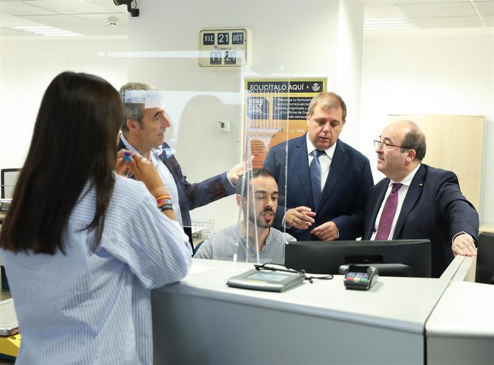 El ministro de Cultura y Deporte, Miquel Iceta (d); el  director de productos y servicios de Correos, Manuel Zapatero (i); y el presidente de Correos, Juan Manuel Serrano (2d), atienden a una joven en la oficina de Correos  de la calle Guzmán el Bueno.