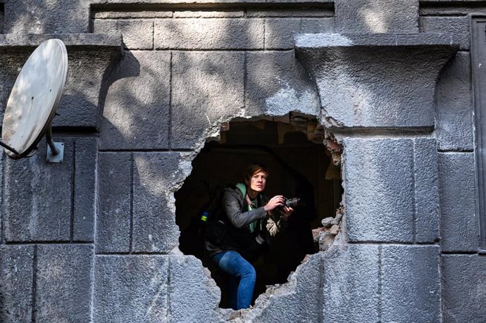 21 October 2022, Ukraine, Zaporizhzhia: A journalist peeps out from the hole in the wall of a residential building damaged as a result of a rocket attack by the russian troops. Photo: -/Ukrinform/dpa