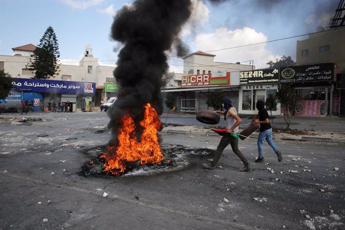 20 October 2022, Palestinian Territories, Nablus: Palestinian protesters clash with Israeli forces in the village of Deir Sharaf near the western entrance of the city of Nablus in the West Bank as they attempt to remove a barrier erected by Israeli forc