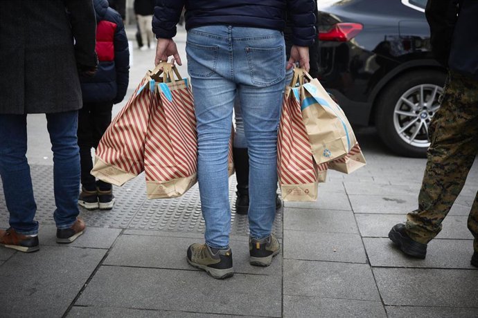Archivo - Una persona con bolsas en una calle comercial 