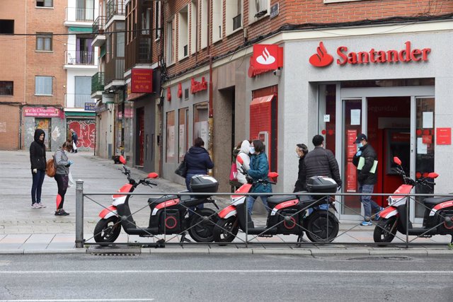 Archivo - Varias personas esperan para entrar a una oficina del Banco Santander durante el inicio de la cuarta semana del estado de alarma decretado a consecuencia del coronavirus. En Madrid (España), a 6 de abril de 2020.