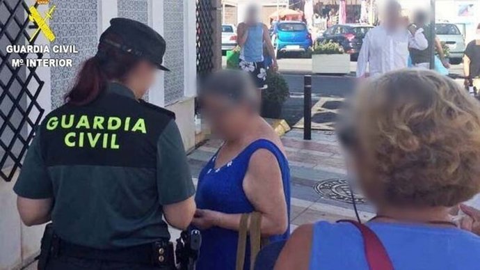 Archivo - Una agente de la Guardia Civil asiste a una mujer en la calle.