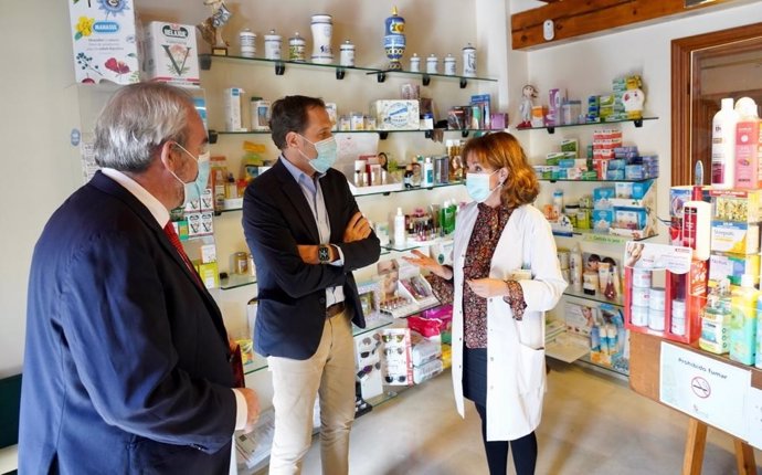 El presidente del Colegio Oficial de Farmacéuticos de Valladolid, Alejandro García Nogueiras (I), y el de la Diputación, Conrado Íscar, en una farmacia de Tiedra.