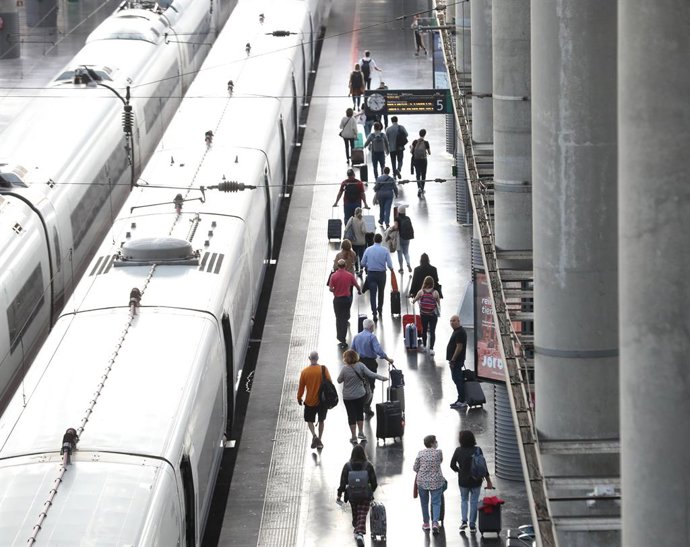 Diversos passatgers amb maletes en l'andana d'un tren