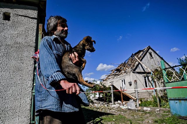 Archivo - Un hombre y su perro frente a las casas afectadas por la caída de un misil ruso en Zaporiyia.